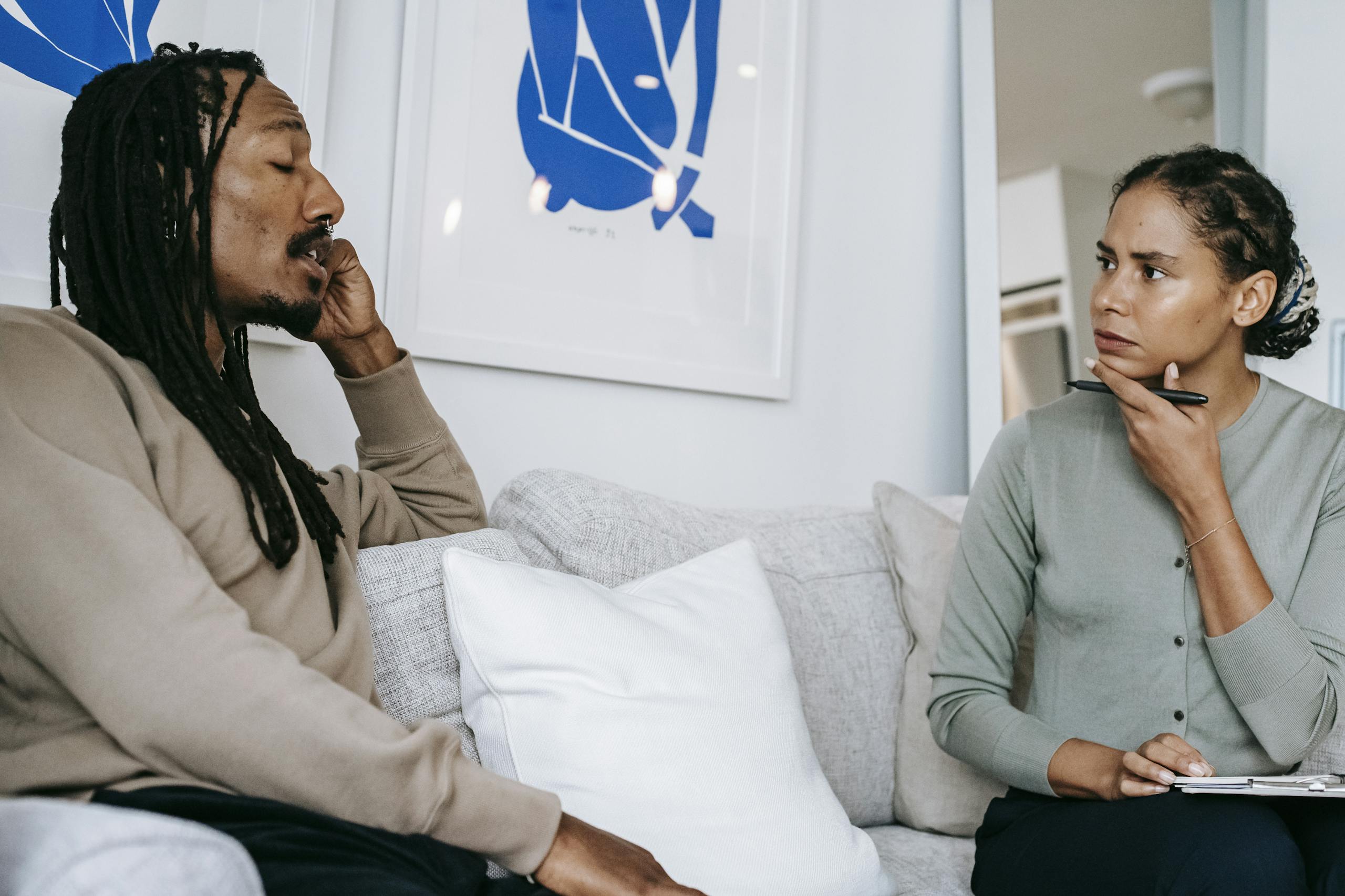 A focused therapy discussion between a male client and female therapist in a serene office.