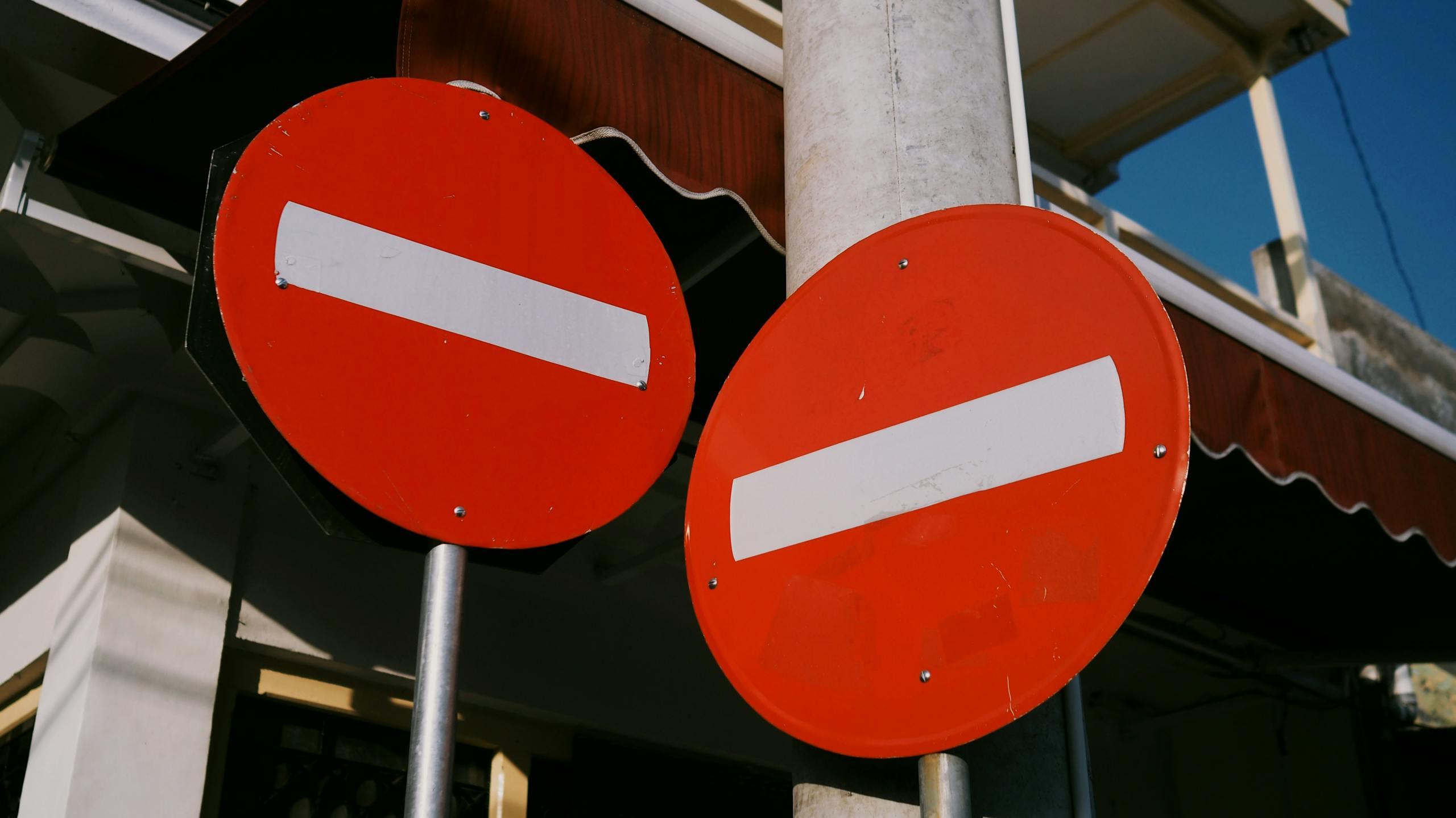 Red no entry signs against a blue sky in an urban Indonesian setting, capturing city life.