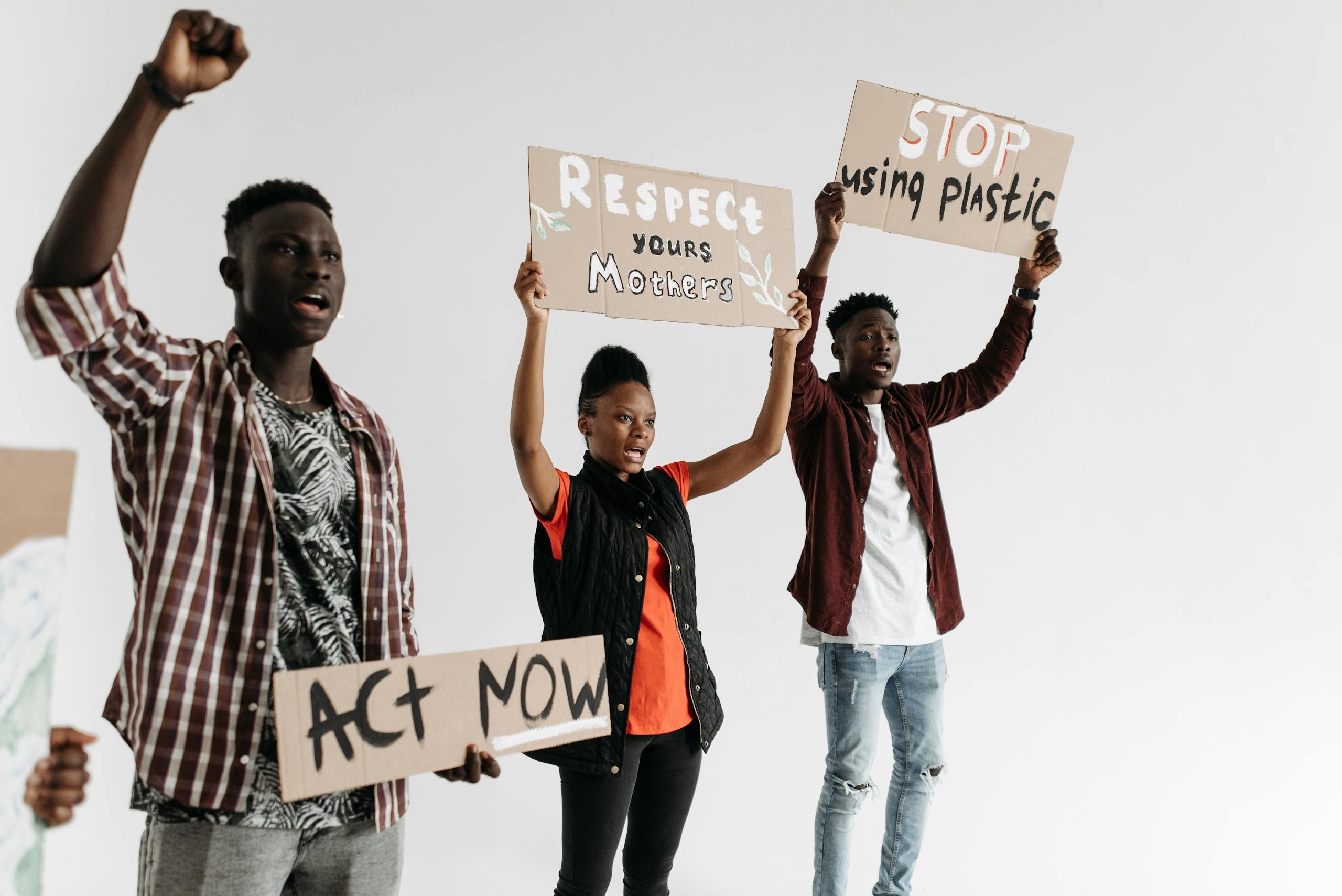 Young adults holding protest signs advocating for respect and environmental awareness.