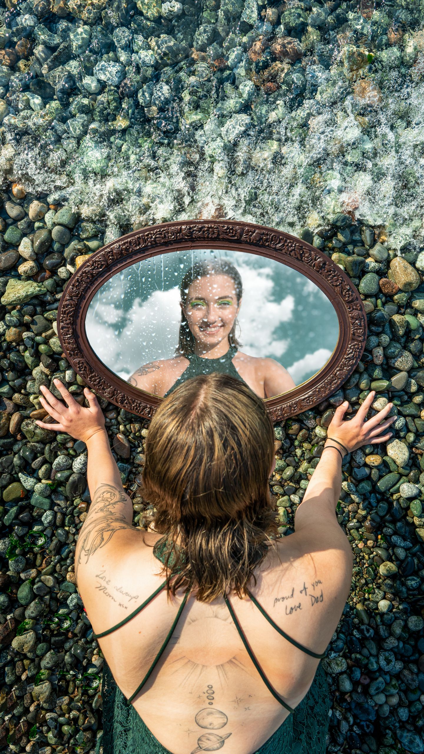 A woman looks into a mirror on a rocky shore, with ocean waves creating a serene scene. Self knowing