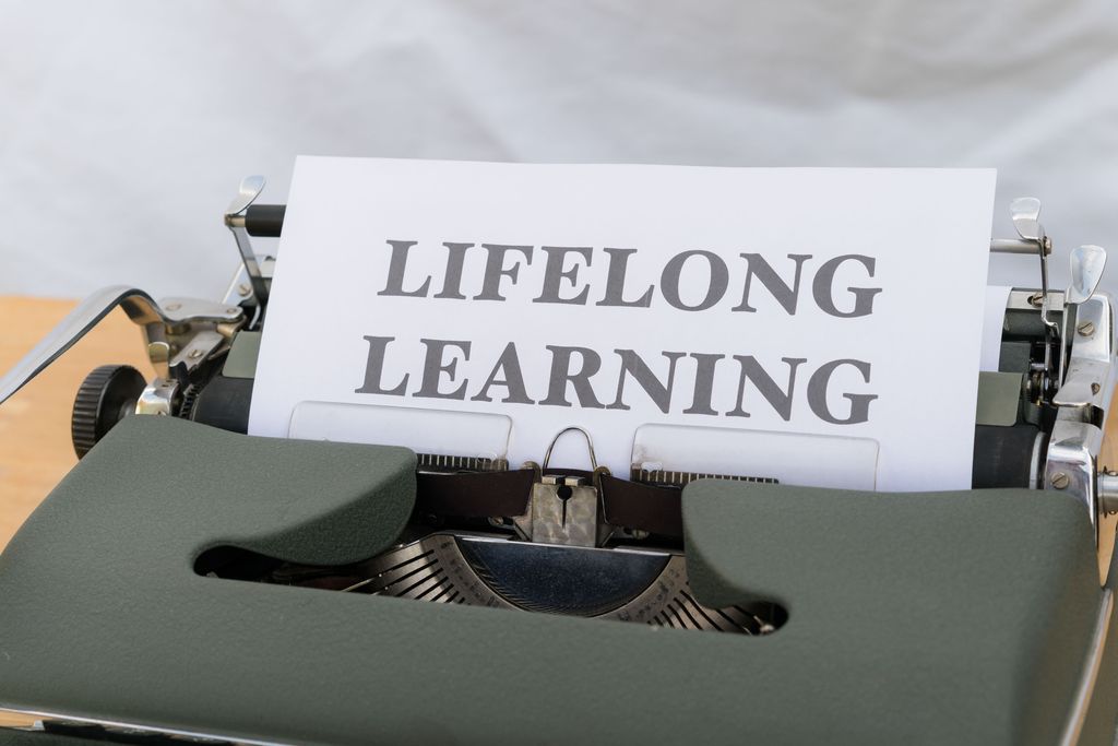 Close-up of a vintage typewriter displaying'Lifelong Learning' on paper. ongoing process self knowing